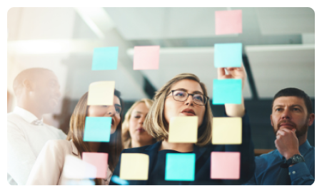 Woman stands in front of glass and puts sticky notes on it