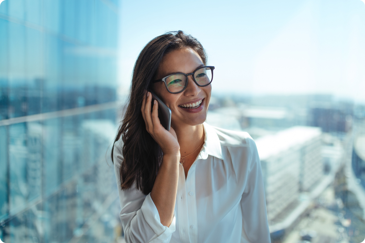 Woman speaking on a phone in front of a skyscraper