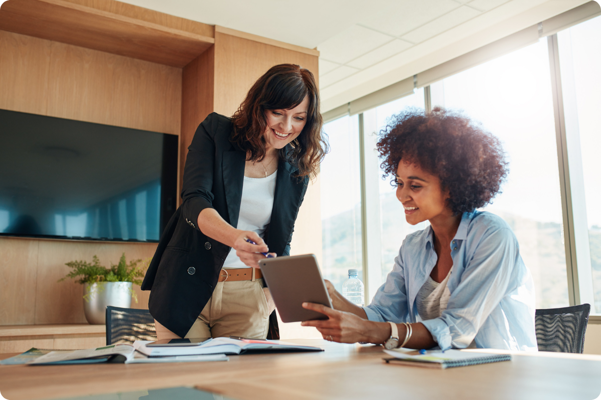 two women looking at a tablet together in an office