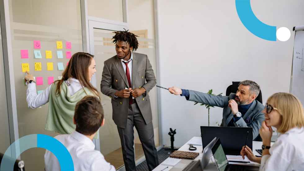 Marketing profesionals in a meeting room talking about post it notes on a board