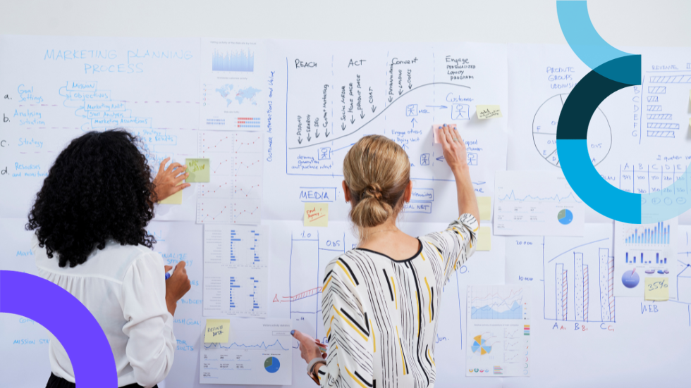 Two women standing at a white board doing marketing planning